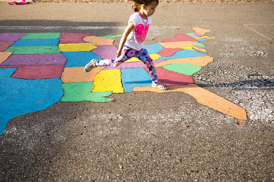 Girl stepping on painted ground map, USA