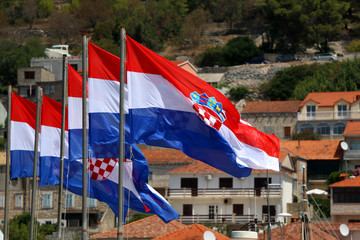 Croatian flags in a row, blowing in the wind. Defocused houses in the background. In Vela Luka, Korcula island, Croatia. 
