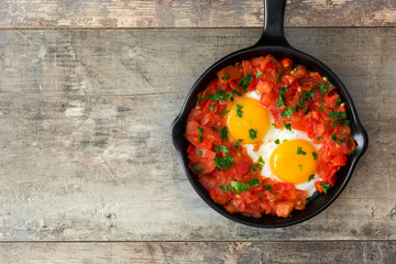 Shakshuka in iron frying pan on wooden table. Typical food in Israel.
