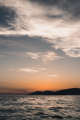 Beatiful evening horizon of sea, island silhouette and big skyline, passed sunset, unique low perspective, warm and dark toting, vertical crop. Hvar Island, Croatia.