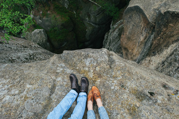 traveler couple hugging while sitting on edge of precipice