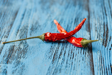 Two red hot peppers on blue wooden background. .Spice concept