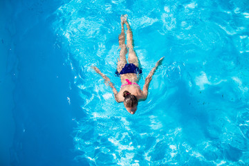 Top view of a girl diving in the swimming pool. Summer day