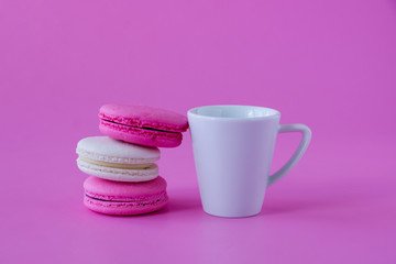 Colorful macaroons and cup of coffee on pink paper backround