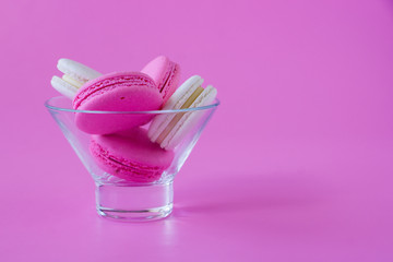 Colorful macaroons in a glass vase on pink background. Concept of romance