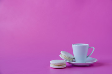 Fototapeta na wymiar Cup of coffee and white macaroons on pink background. Space for text