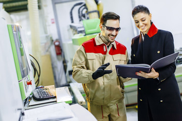 Young woman controlling process in the factory with male worker