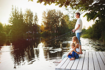 Fototapeta na wymiar Young happy family with kids fishing in pond in summer