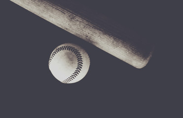 Wooden baseball bat and ball against black backdrop, vintage matte style.  