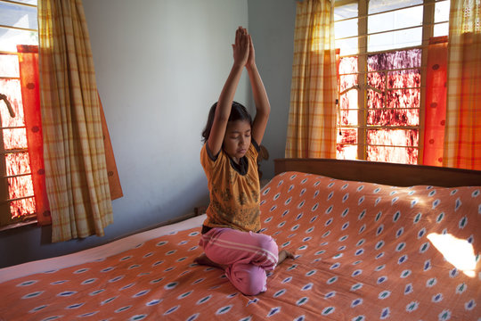 A little girl doing Yoga inside house