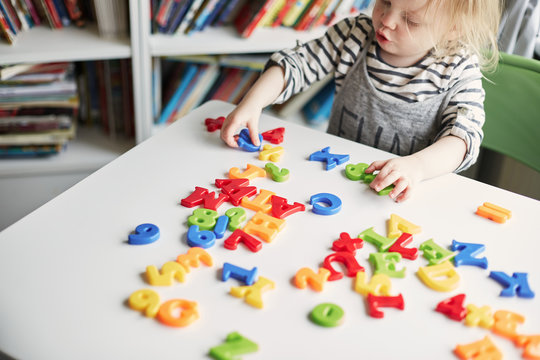 Little toddler girl playing with coloured letters