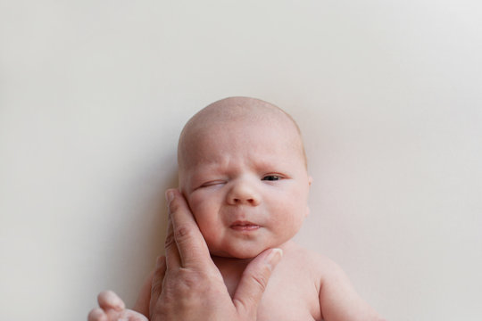 mother's hand stroking cheeks of her newborn baby