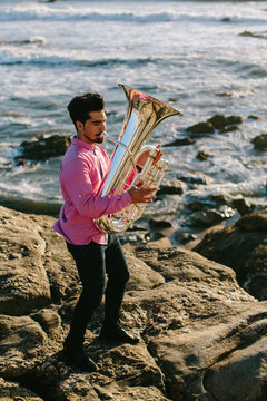 Outdoor Portrait of musician with tuba wind musical instrument. Sea shore, Atlantic Ocean