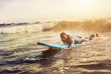 Handsome man has surfing on small waves. Mixed race dark skin and beard. Summer sport activity