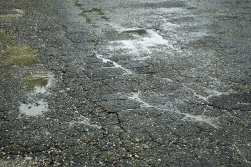 nasse Straße mit Frostschäden