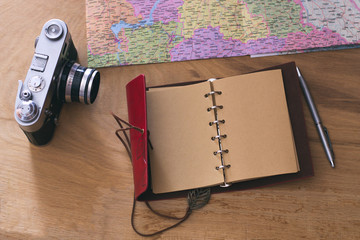 Traveler's things: old camera, map, notebook on a wooden background