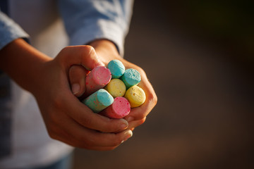 Closeuop childs hands holding colored chalks for drawing.
