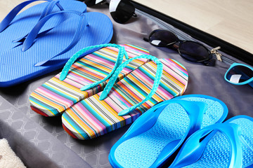 Open suitcase with flip-flops and sunglasses, closeup. Summer vacation concept
