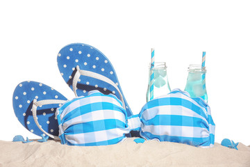 Fototapeta na wymiar Swimsuit, flip-flops and cold drinks on sand against white background. Summer vacation concept