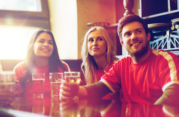 fans or friends watching football at sport bar