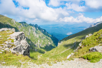 Fototapeta na wymiar Panoramic view over the Carpatian mountains, green valleys and beautiful blue sky at the background, Bucegi natural park, Romania, on sunny summer day.