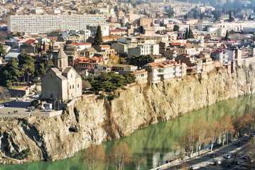 A view over the roofs of old houses, Mtkvari (Kura) river and Metekhi church in the center of Tbilisi, Georgia, and a sunrise early in the morning. © Victoria
