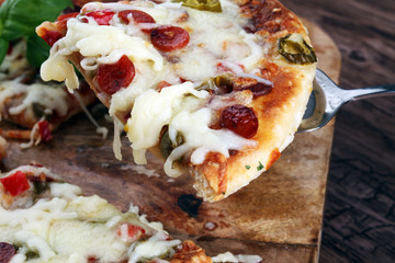 Hot pizza slice with melting cheese on a rustic wooden table. Italien food concept