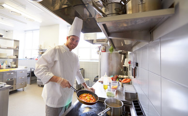 happy male chef cooking food at restaurant kitchen