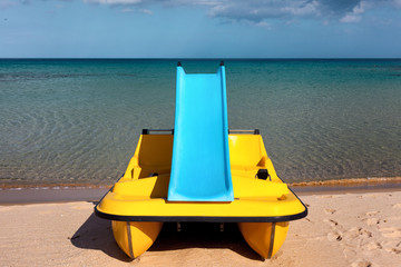 Fototapeta premium Paddle boat with water slide on the calm sea beach