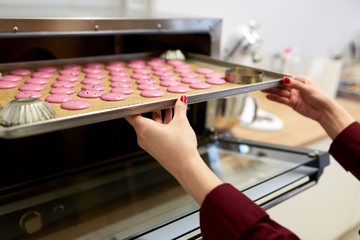 chef with macarons on oven tray at confectionery