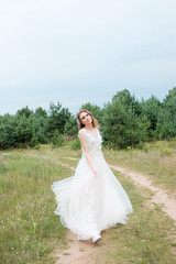 Fototapeta na wymiar young pretty woman (bride) in white wedding dress outdoors, make up and hairstyle