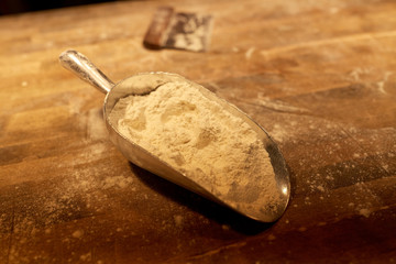 flour in bakery scoop and dough cutter on table