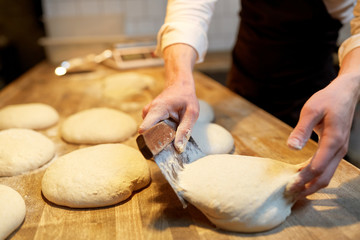 baker portioning dough with bench cutter at bakery