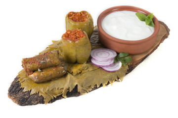 Sarma/ Stuffed Vine Rolls and Dolma/ Stuffed Green Pepper with Yoghurt and Sliced Red Onion on a Wooden Plate, White Background