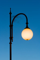 street light on in the twilight on the blue sky background