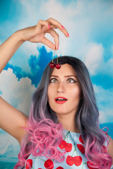 joyful young pin up girl eating sweet cherry standing alone