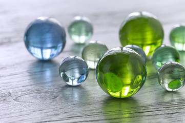 Glass balls of green and blue on a wooden surface.