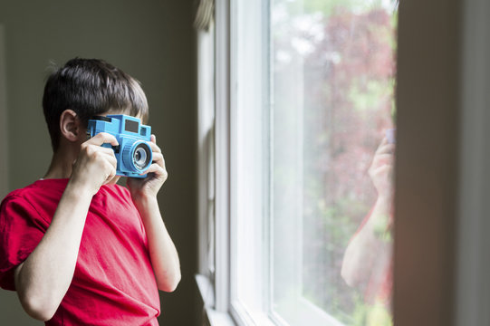 Boy taking picture while standing at window