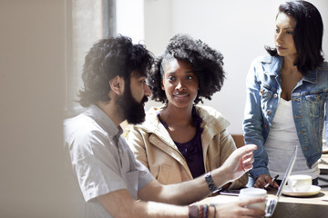 Businesswomen looking at male colleague explaining in office cafeteria