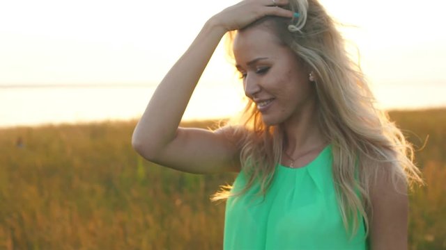 beautiful blonde walking in a field at sunset,close-up
