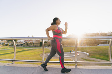 Side view of woman jogging on elevated walkway against clear sky