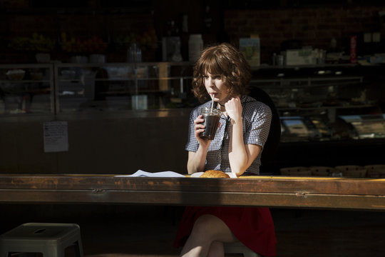 Woman looking away while drinking cola in cafe