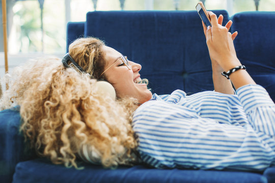 Side view of woman using smartphone while lying on sofa at home