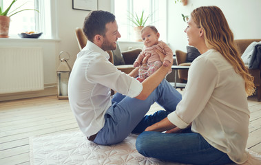 Smiling young parents sitting with their baby girl at home