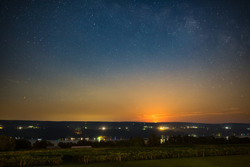 Moon rising over vinyard and lake under stars and milky way