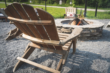 Wooden adirondack chair next to a fire pit in the woods