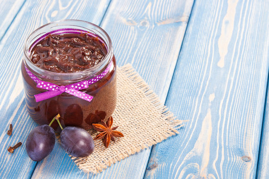 Fresh homemade plum jam in glass jar, healthy dessert concept, copy space for text on boards