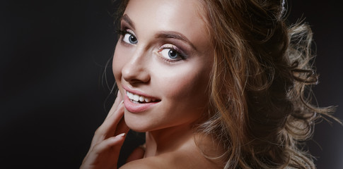 Beautiful woman with curly long hair on dark background