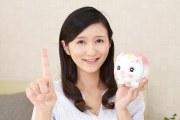 貯金箱を持つ笑顔の女性