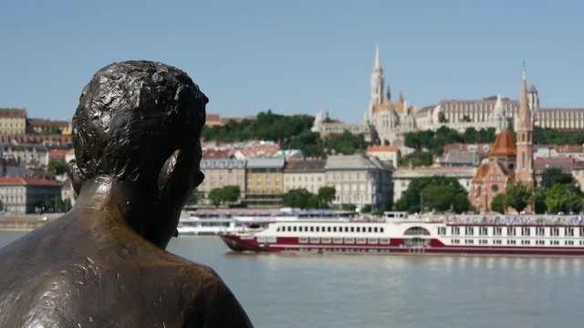 Statue of Attila Jozsef, one of the country's best-loved 20th century poets in Budapest with a cruise ship passing by in Hungary